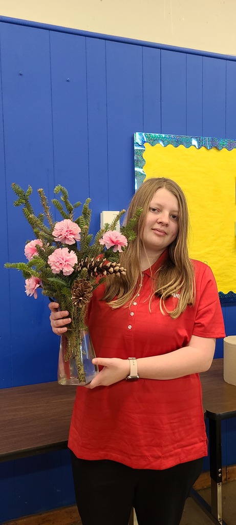 High school student holds an arrangement of pink and pink silk flowers 