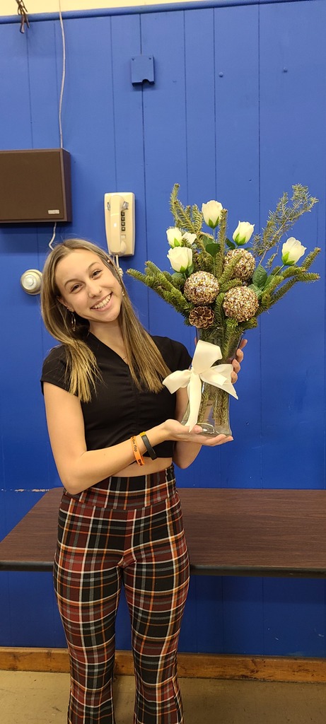 High School student holds an arrangement of pine and silk roses 