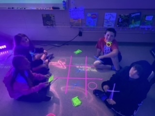 Students review for a test under black lights 