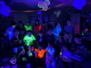 fourth grade students gather for a picture in black light 