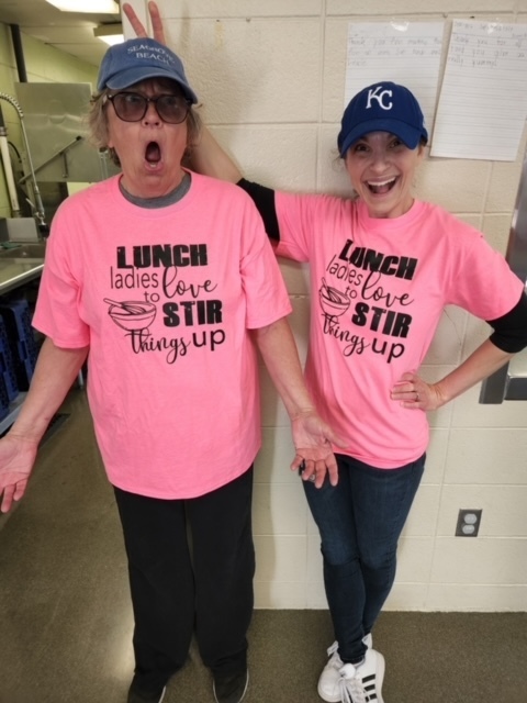 Two lunch ladies in shirts that read "Lunch Ladies Stir Things Up" 