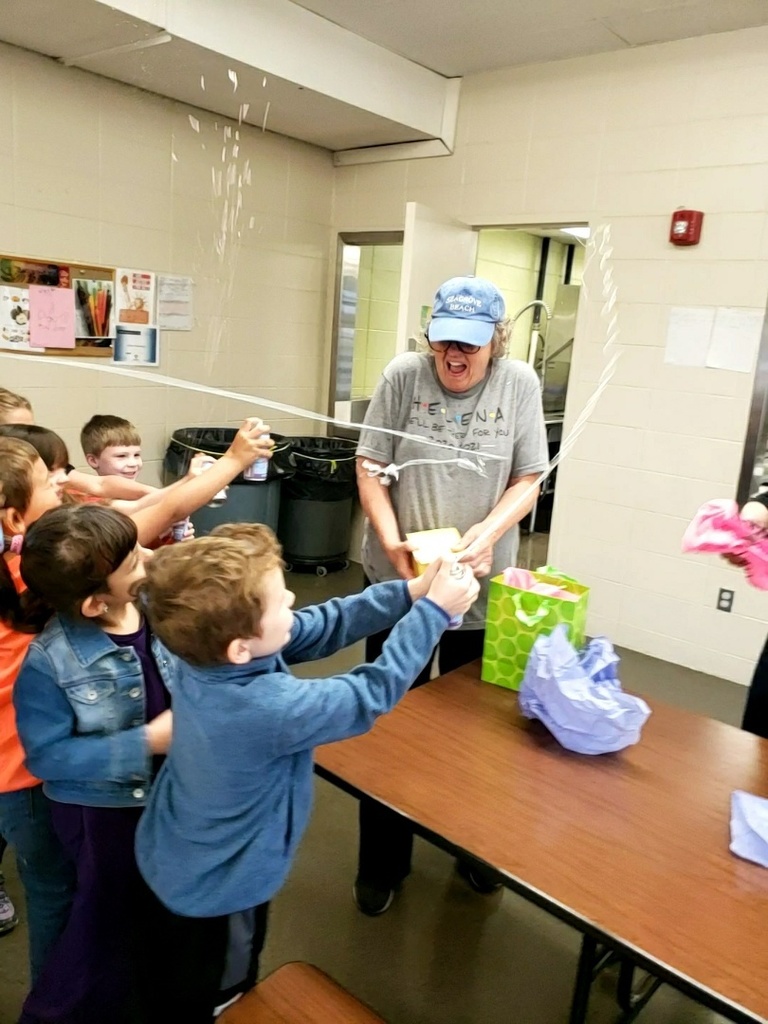 Students silly string Sue Modlin as she opens her gift 