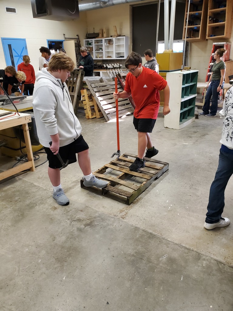 two students breaking apart pallets