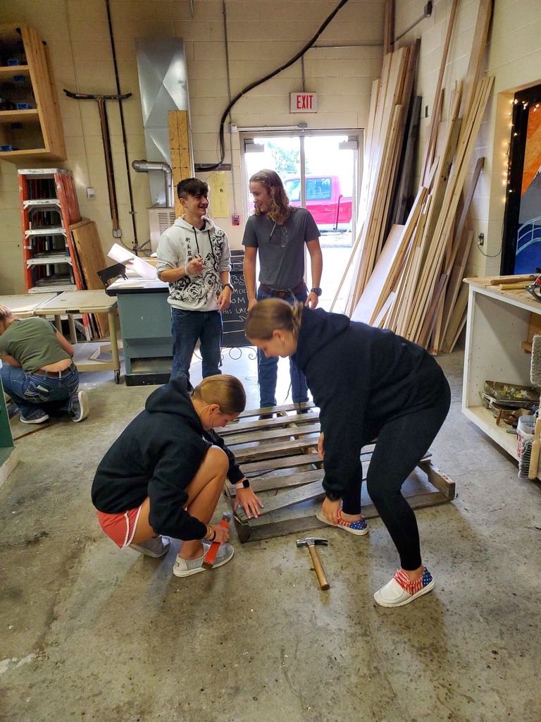 two students take wood off of pallets