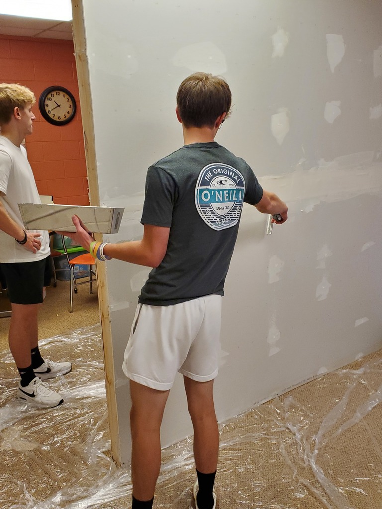Students mud a new drywall wall in the counseling center at the high school 