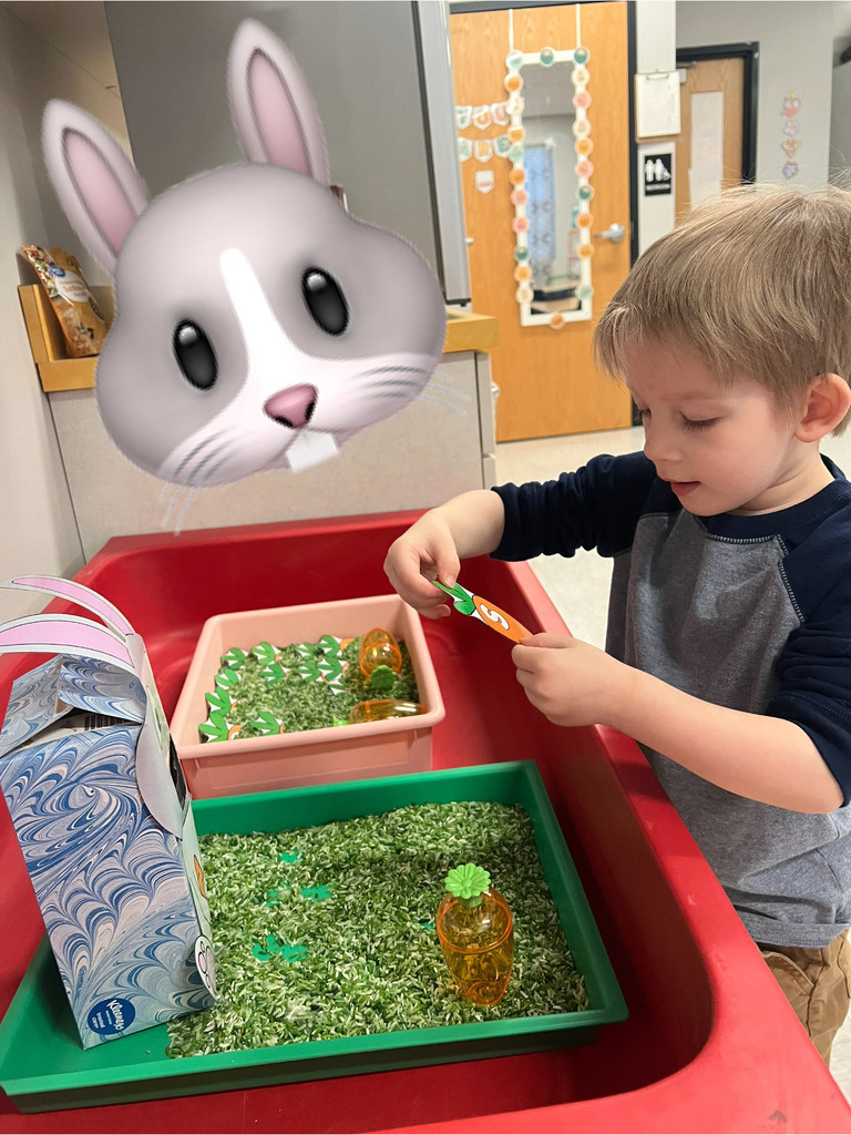 small young boy looks at a picture of a carrot with the letter s on it.  There is a large cartoon bunny in the corner of the image.  